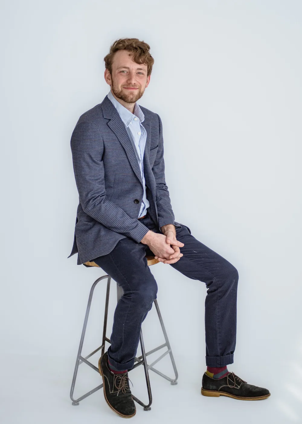 Jordan Lovinger seated on a stool in a blazer