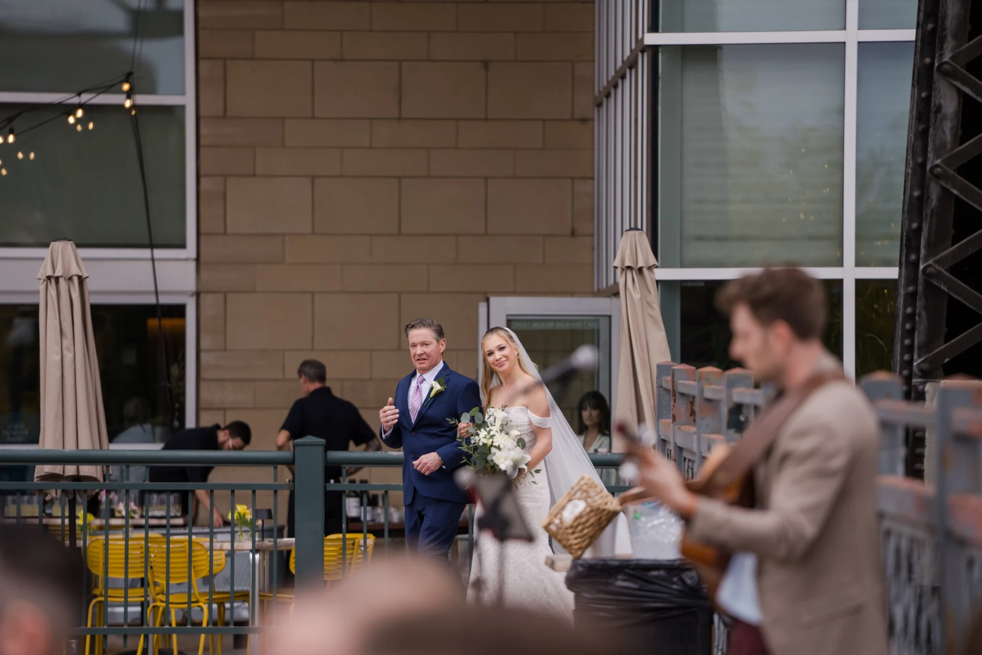 A bride walks in on her father's arm while Jordan plays the processional on guitar
